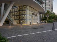 a large building surrounded by tall buildings near a manhole on a walkway in a city