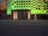 the green lights on the facade of the building glow off in front of the parking meter