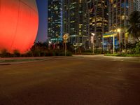 empty city street in front of brightly colored building at night time on beachfront with large pink ball