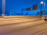 a blurry photo shows the city as the train is passing by at night near a light