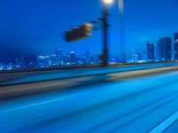 a blurry photo shows the city as the train is passing by at night near a light