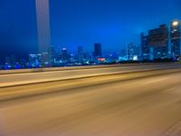 a blurry photo shows the city as the train is passing by at night near a light