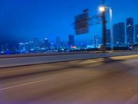 a blurry photo shows the city as the train is passing by at night near a light