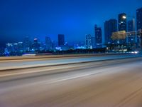 a blurry photo shows the city as the train is passing by at night near a light