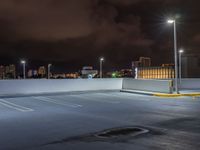 the parking lot is empty during the night with city lights on it's roofs