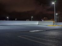 the parking lot is empty during the night with city lights on it's roofs