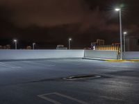 the parking lot is empty during the night with city lights on it's roofs