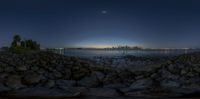 a scenic view of a beach at night with a full moon setting over the water