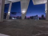 a large cement structure with multiple angles of roof top with a city skyline in the background at sunset