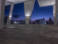 a large cement structure with multiple angles of roof top with a city skyline in the background at sunset