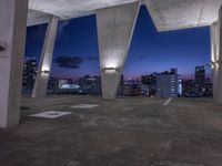 a large cement structure with multiple angles of roof top with a city skyline in the background at sunset