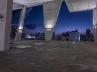 a large cement structure with multiple angles of roof top with a city skyline in the background at sunset