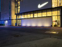 the front of the nike store is very lit up at night and is now lit