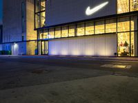 the front of the nike store is very lit up at night and is now lit