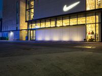 the front of the nike store is very lit up at night and is now lit