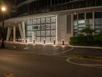 an exterior of a building at night with people walking near it on the side walk