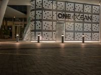 the word home stands out against a decorative wall at night in front of a shopping center