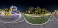 this is a 360 - view panoramic shot of an intersection at night with palm trees in the background