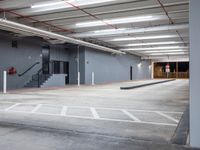 empty parking lot with stairs on side of building next to stairs and exit doors on wall