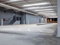 empty parking lot with stairs on side of building next to stairs and exit doors on wall