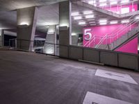 an empty parking lot with stairs and signs near it in the building at night hours