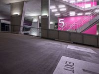 an empty parking lot with stairs and signs near it in the building at night hours