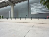 a woman is skateboarding down an empty concrete road with a large concrete building behind her