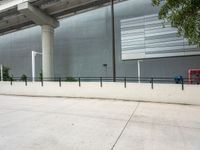 a woman is skateboarding down an empty concrete road with a large concrete building behind her