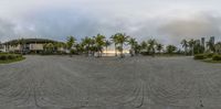 a circular image of a plaza with a building in the distance with palm trees in the middle