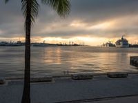 a body of water with a large ship in the background in a bay during sunset