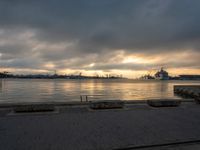 a body of water with a large ship in the background in a bay during sunset