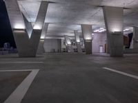 an empty parking space with lots of concrete pillars and lighting on the walls as seen from the ground