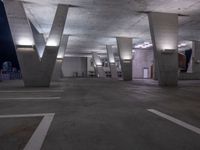 an empty parking space with lots of concrete pillars and lighting on the walls as seen from the ground