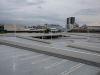 an empty parking lot with several poles in it and a city skyline behind it as seen from a roof of a building