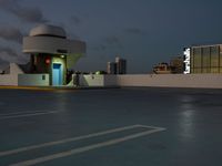 an empty parking lot and a building is shown in the evening with street lights on