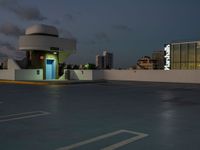 an empty parking lot and a building is shown in the evening with street lights on