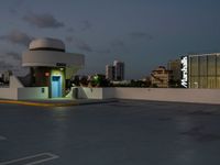 an empty parking lot and a building is shown in the evening with street lights on