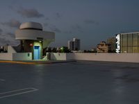 an empty parking lot and a building is shown in the evening with street lights on