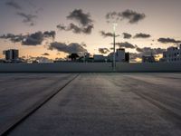 the large open concrete parking lot is in the foreground as the sun sets over the city