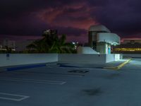 an empty parking lot on top of a building in the middle of town during night time