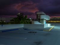 an empty parking lot on top of a building in the middle of town during night time