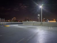 empty parking lot with building lights behind it at night time in urban setting at dusk