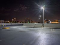 empty parking lot with building lights behind it at night time in urban setting at dusk