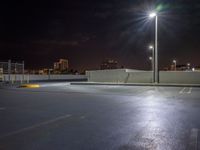 empty parking lot with building lights behind it at night time in urban setting at dusk