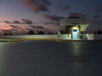 parking garage with no sign at sunset time with clouds in the sky behind it and parking lights in the distance