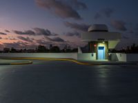 parking garage with no sign at sunset time with clouds in the sky behind it and parking lights in the distance