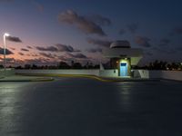 parking garage with no sign at sunset time with clouds in the sky behind it and parking lights in the distance