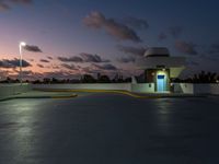 parking garage with no sign at sunset time with clouds in the sky behind it and parking lights in the distance