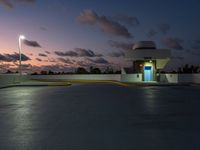 parking garage with no sign at sunset time with clouds in the sky behind it and parking lights in the distance