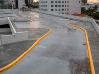 a large parking lot that has yellow and gray poles on it and buildings in the background